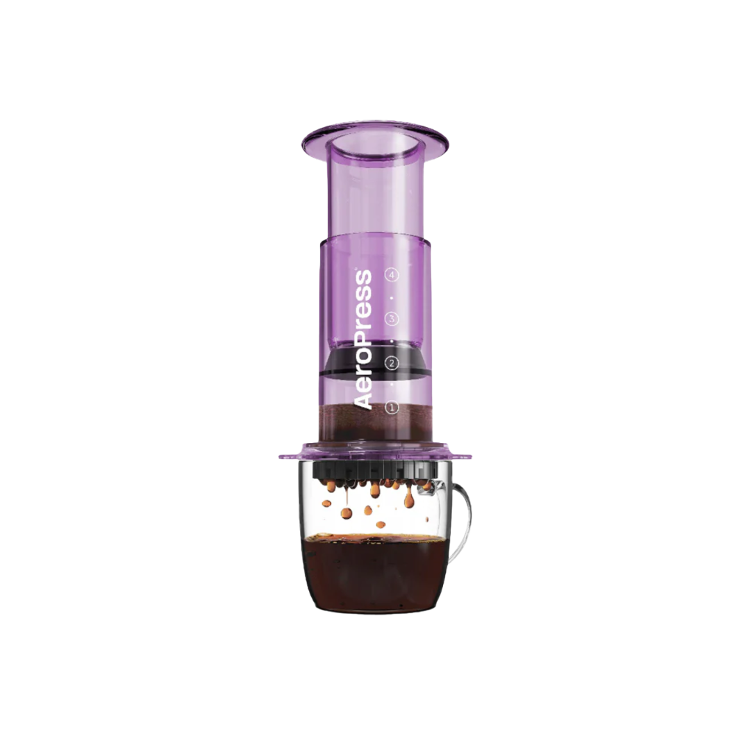 Purple Aeropress coffee maker on a glass mug.