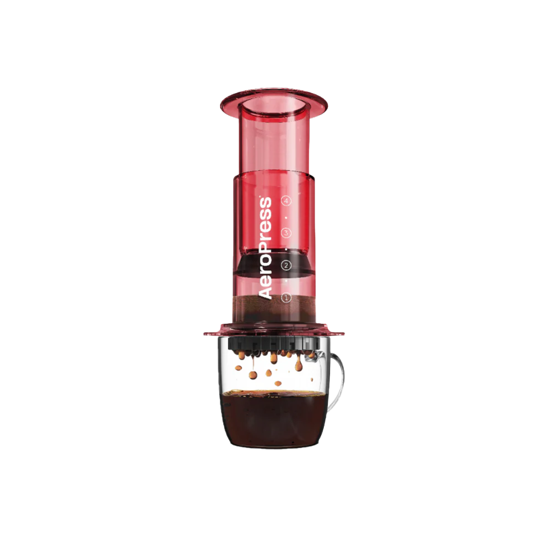Aeropress coffee maker in red on a glass mug of coffee.