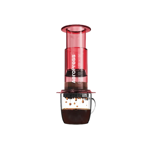 Aeropress coffee maker in red on a glass mug of coffee.