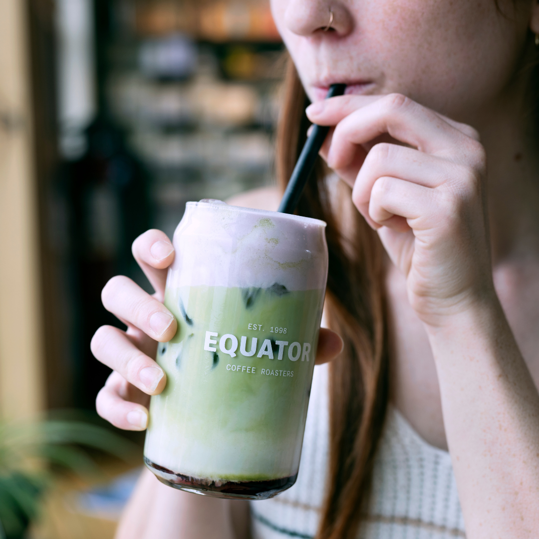 A person sipping on a drink with a black metal reusable straw.