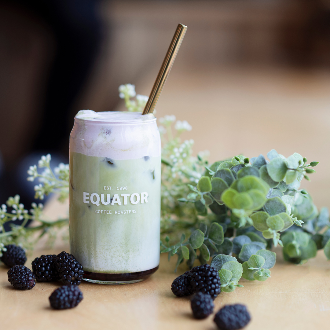 Blackberry matcha drink with a gold coloured metal straw.