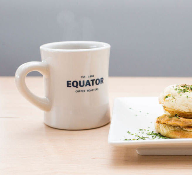 Diner mug with Equator Coffee Roasters and a plate of food to the side.
