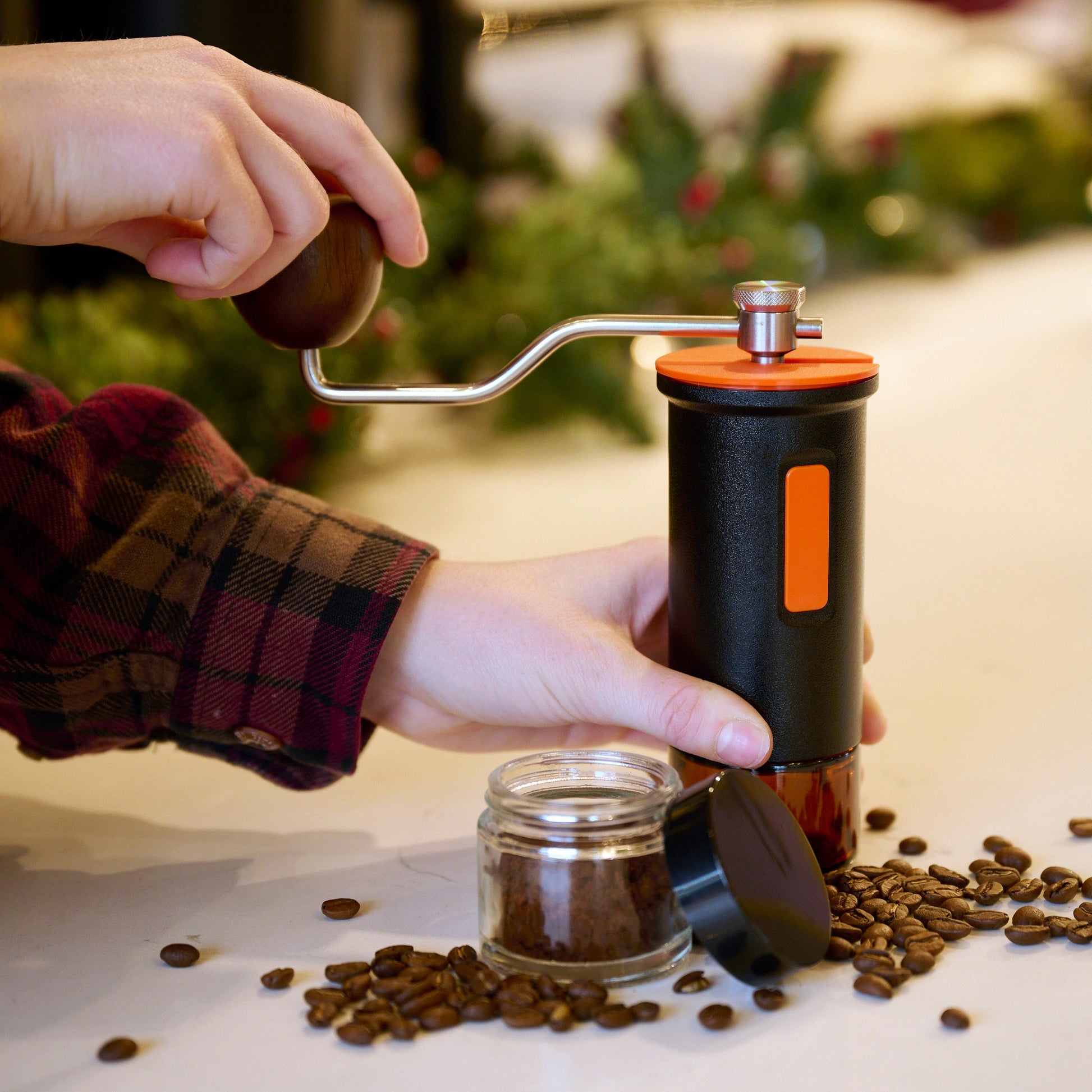 A person using the black Maiwen manual coffee grinder.