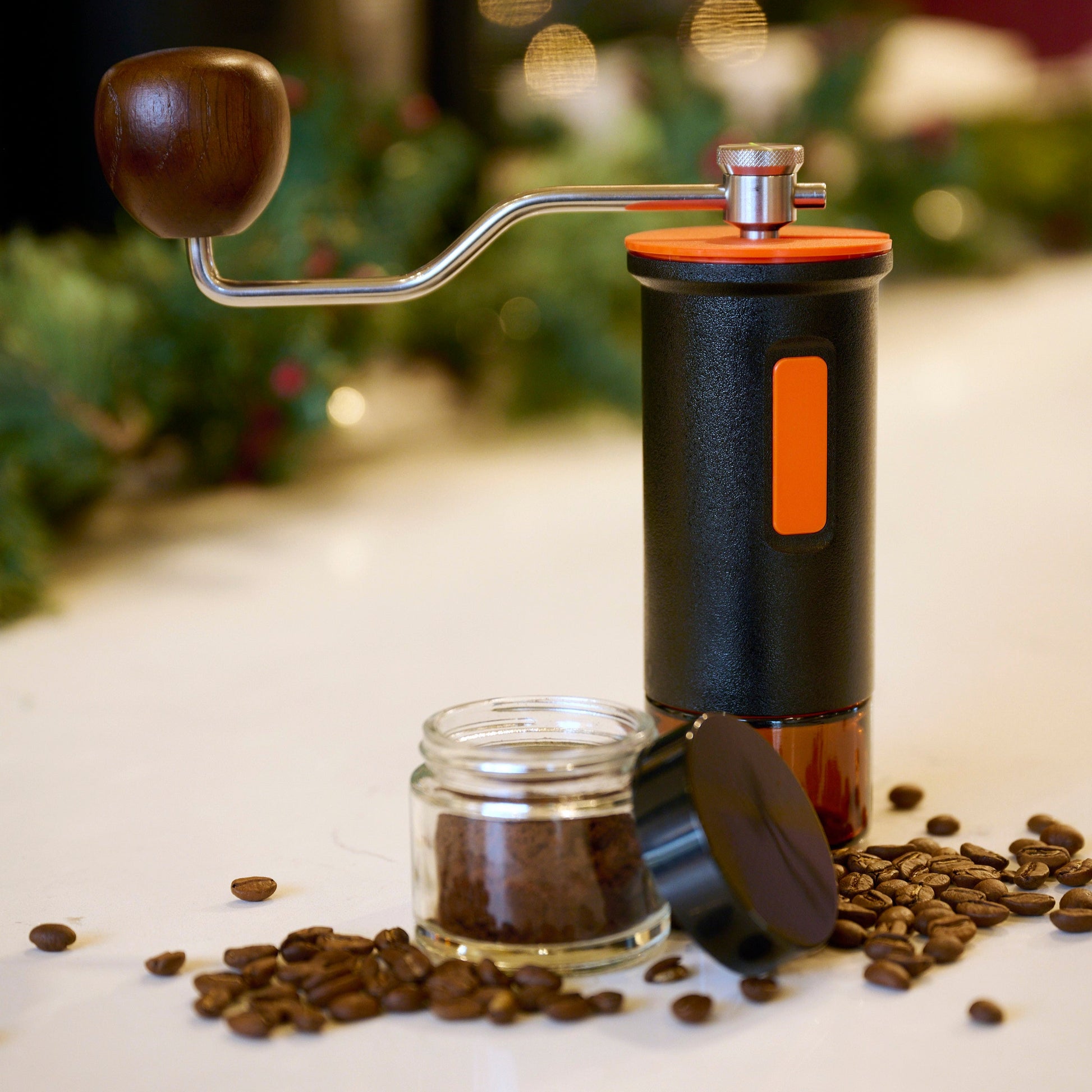 Maiwen manual coffee grinder with some coffee beans around it.