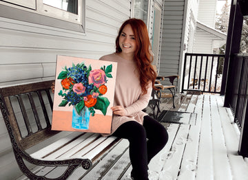 Bailey holding a painting she did of a jar of flowers.