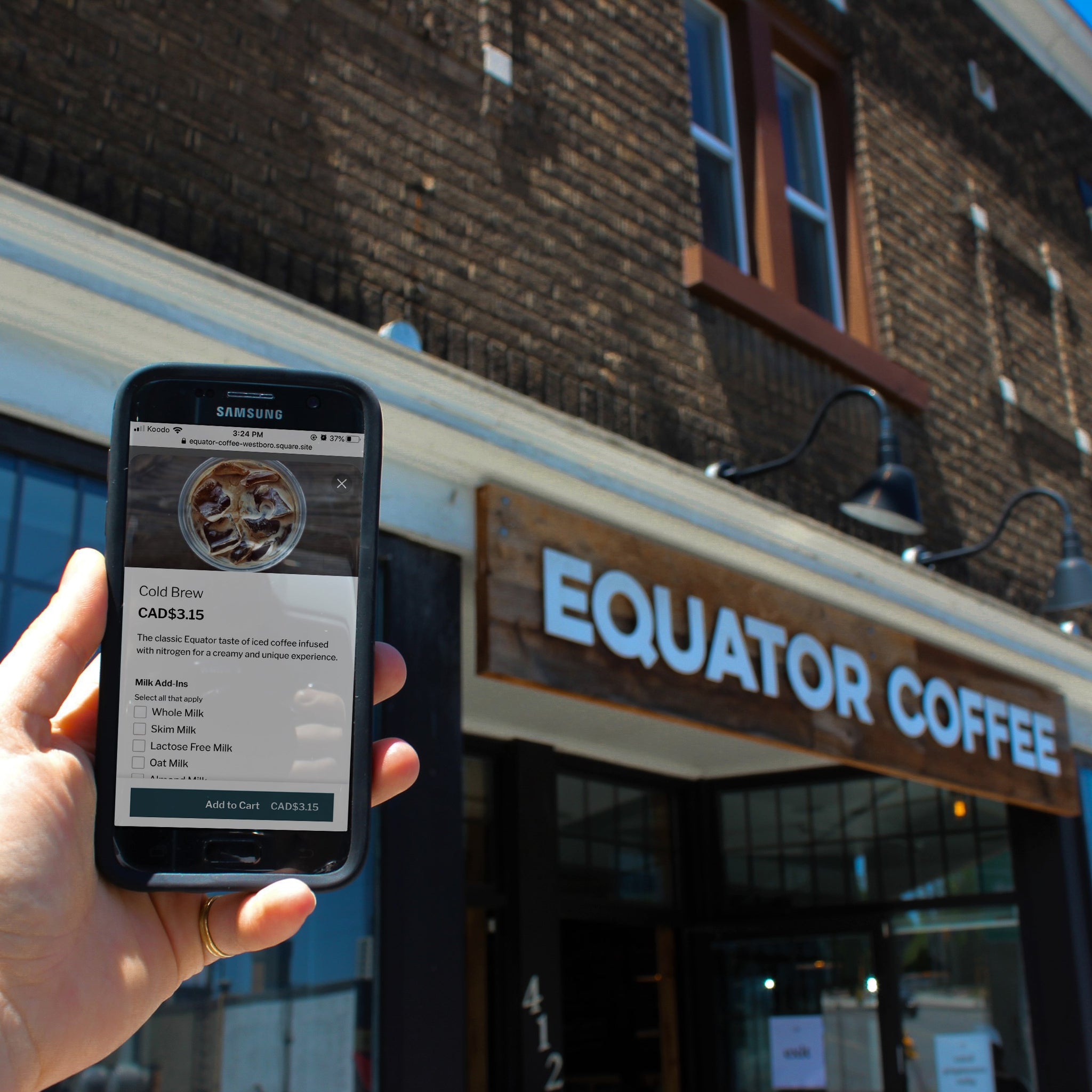A person holding a phone with the Equator App showing, and they are in front one of our cafes.