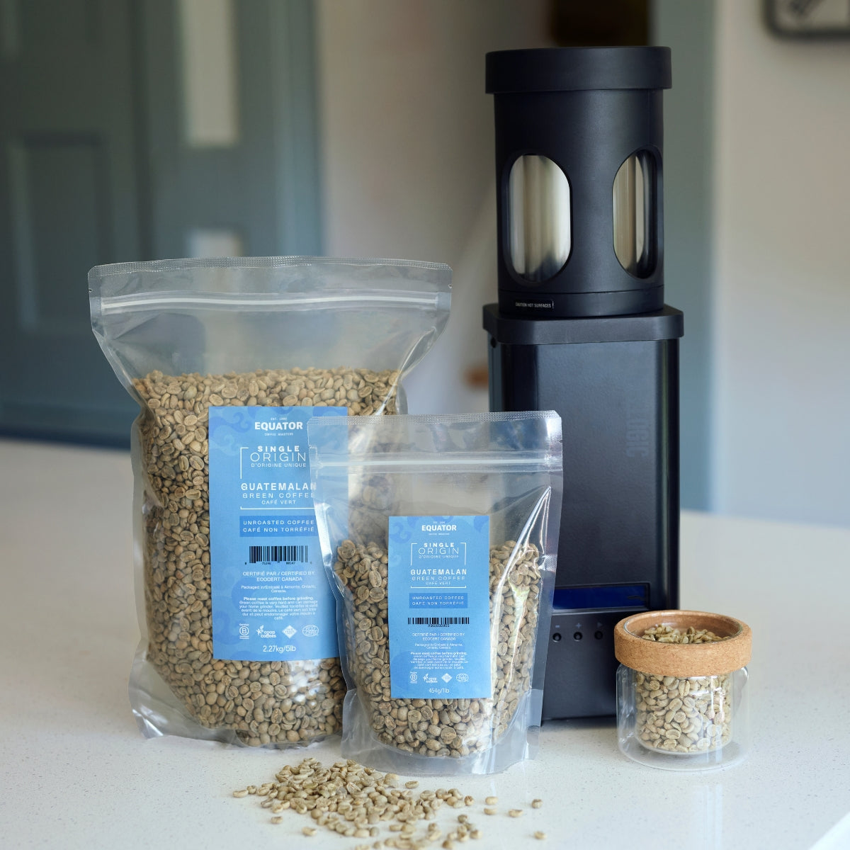 1lb and 5lb resealable packages of green coffee with a black home roaster.