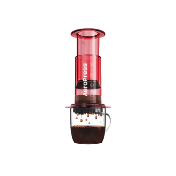 Aeropress coffee maker in red on a glass mug of coffee.