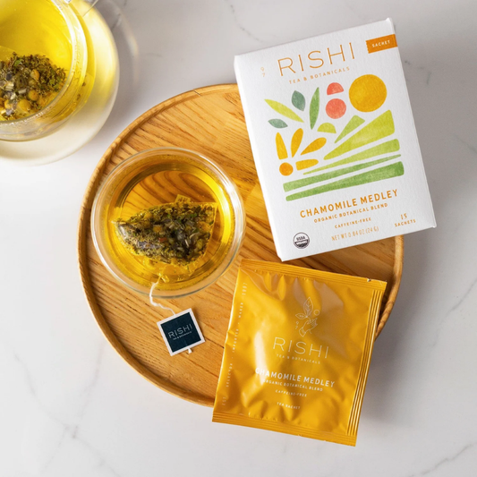 Rishi Chamomile Medley tea packaging with a glass of tea on a wooden tray.