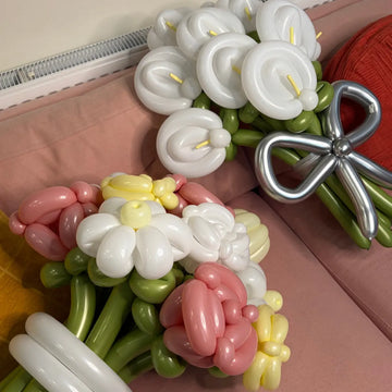 Balloon sculpture of flowers and a bow on a pink surface