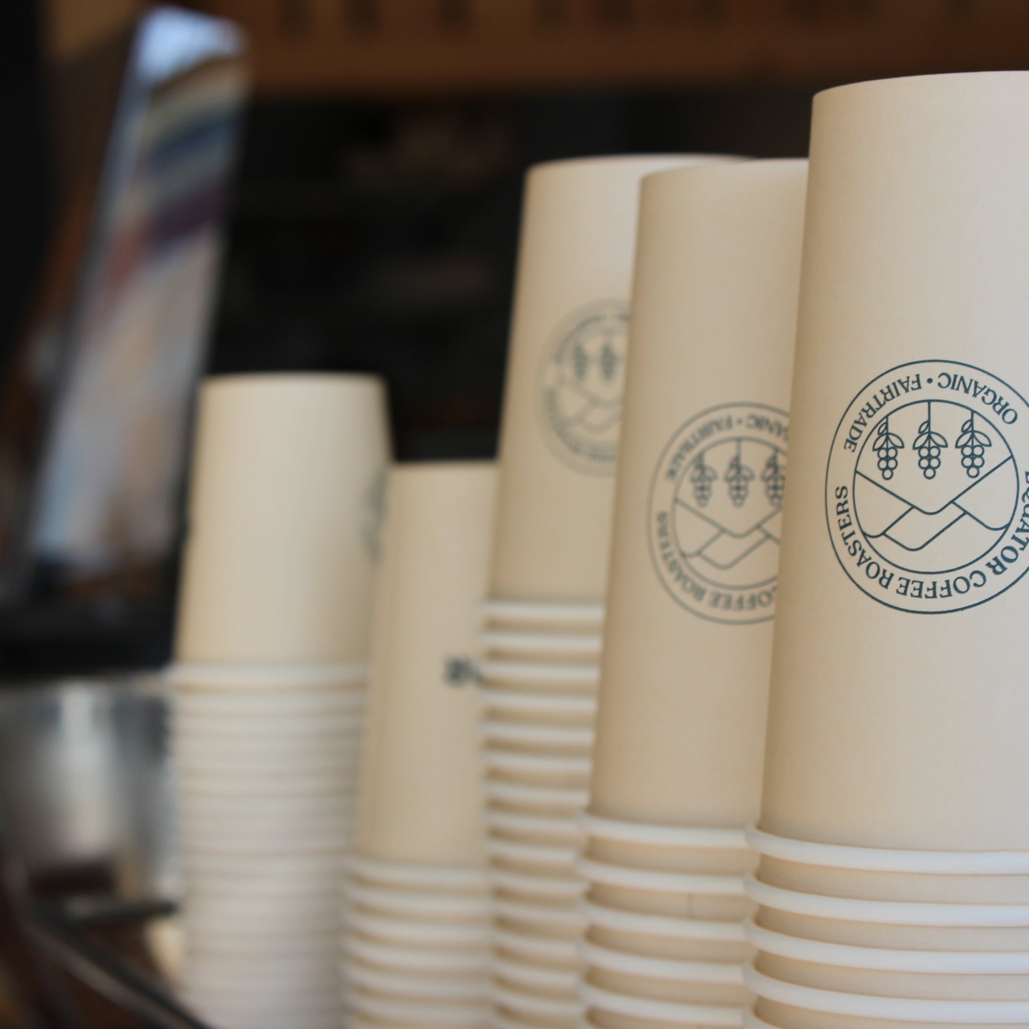 Stacks of compostable hot cups with Equator Coffee Roasters logo.