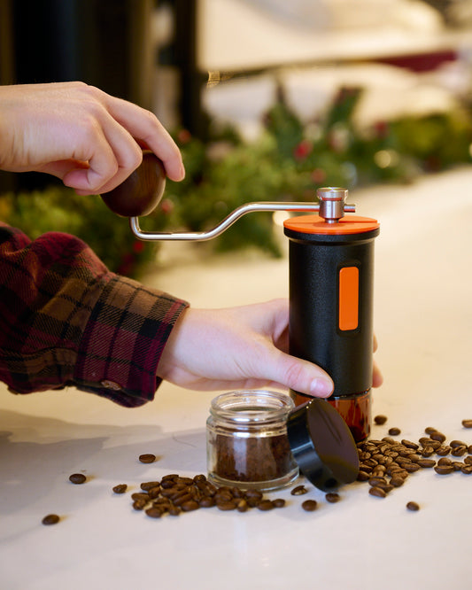 A person using the black Maiwen manual coffee grinder.