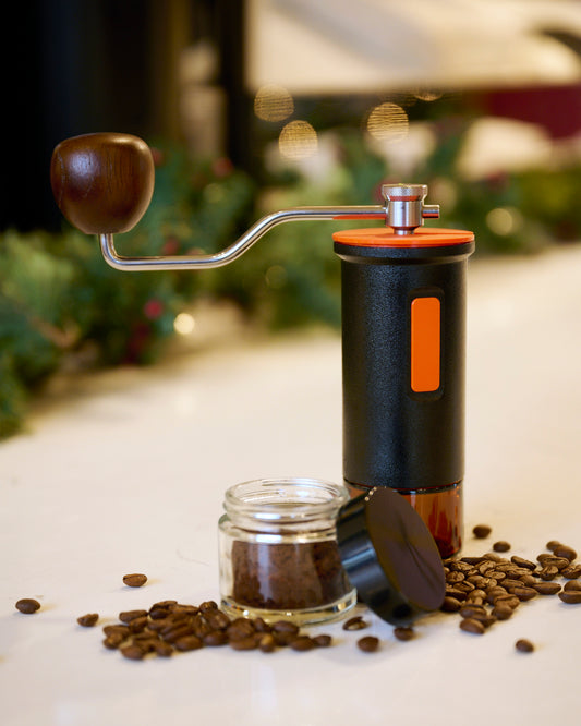 Maiwen manual coffee grinder with some coffee beans around it.